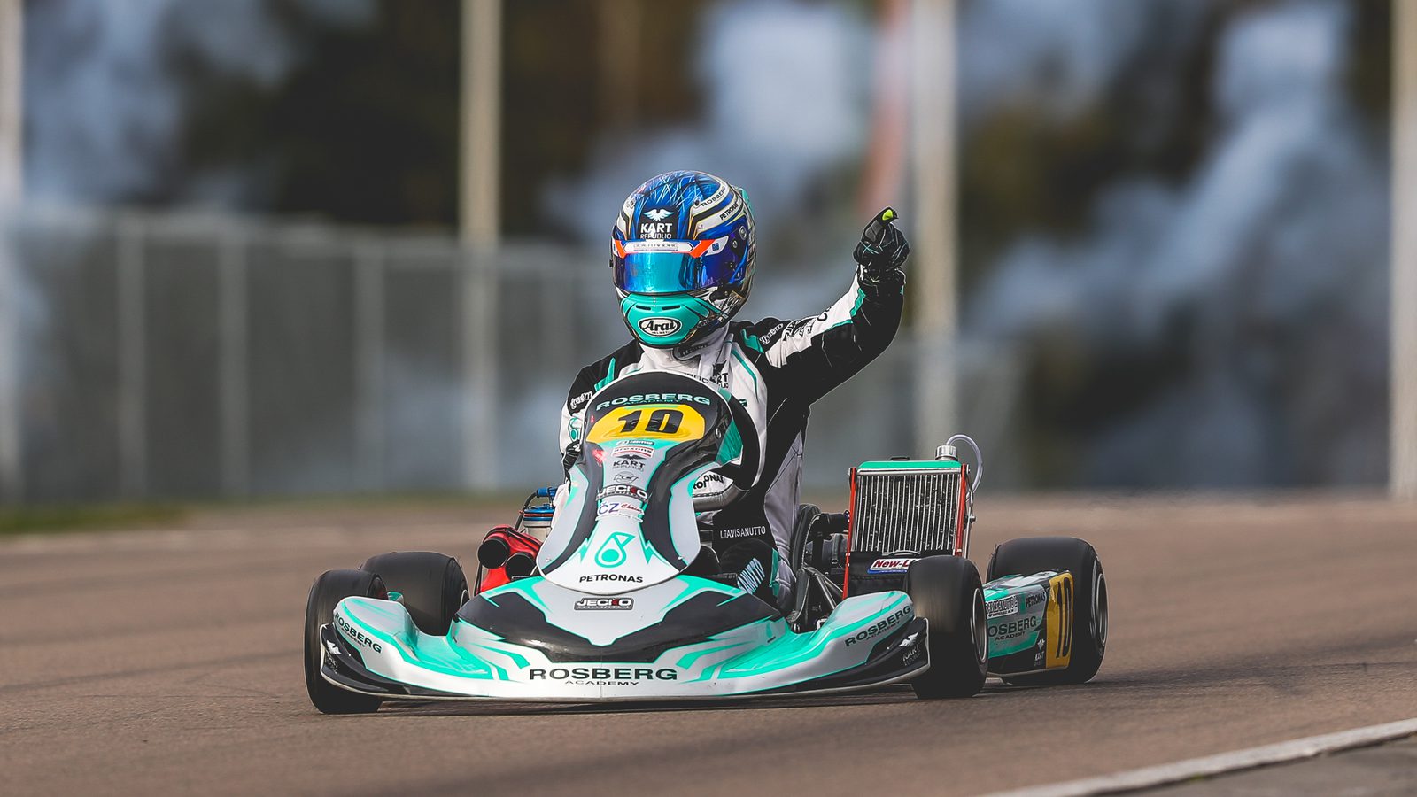 A racing kart at speed, driver's fist raised in victory